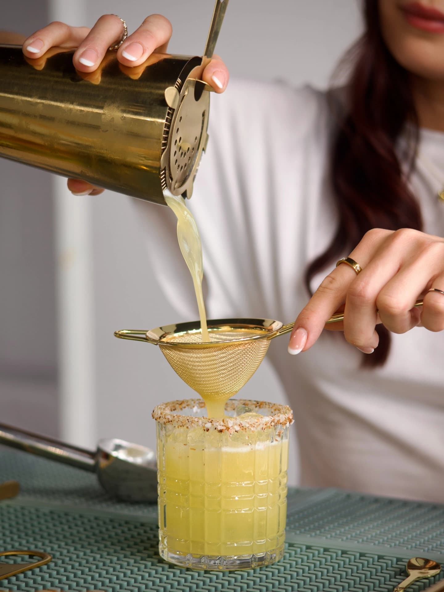 A margarita being strained into a coupe glass, close-up.