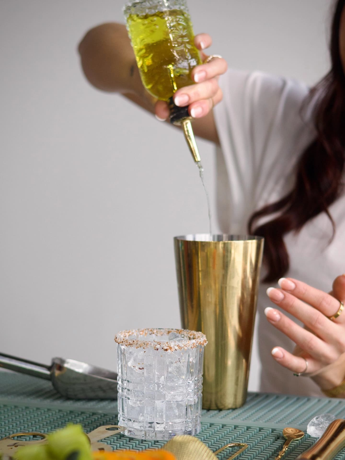 Mixer being poured into a gold cocktail shaker.